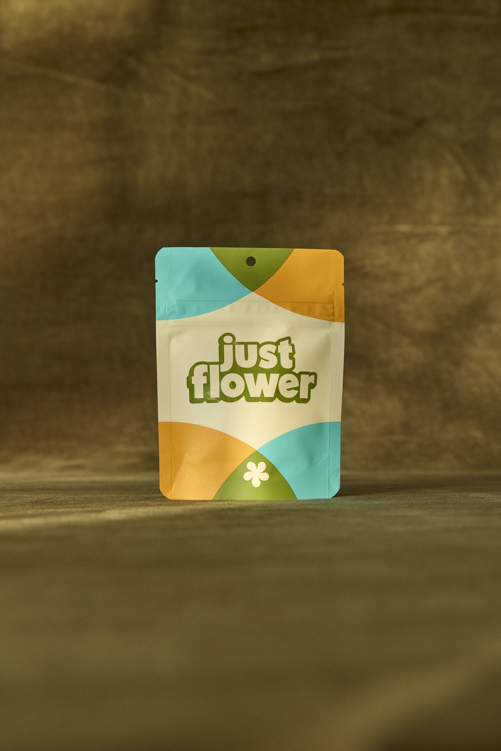 Just Flower cannabis package standing on an olive fabric backdrop