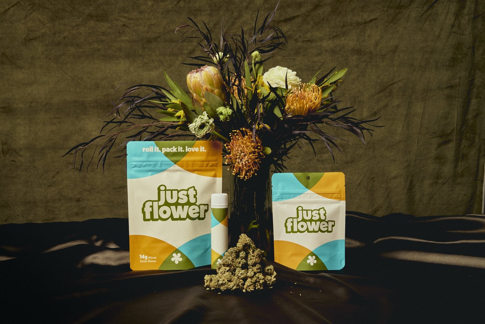 Just Flower cannabis packaging with fresh flowers on a dark backdrop